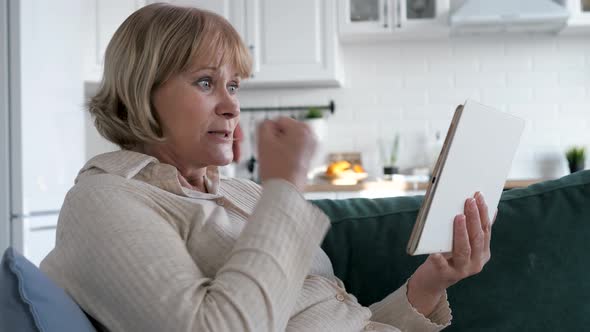 Excited Woman Sitting On Couch With Tablet Beside Herself With Joy Of Success