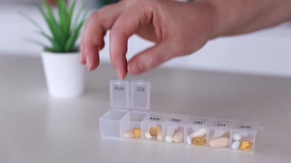 Hand Put Pills to Medical Pill Box Tablet Doses for Daily Take Drugs Capsules