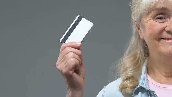 Smiling Aged Female Showing Credit Card on Grey Background, Cashless Payment