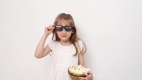 Girl with Glasses to Watch 3D Movies with Popcorn Stands Against White Wall