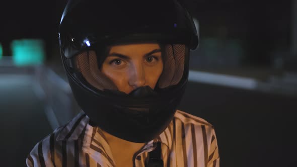 Portrait of Beautiful Young Woman Motorcyclist in Black Motorcycle Helmet in the Night Street