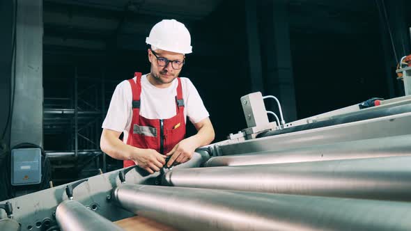 Serviceman is Regulating a Conveyor Machine Relocating Metal