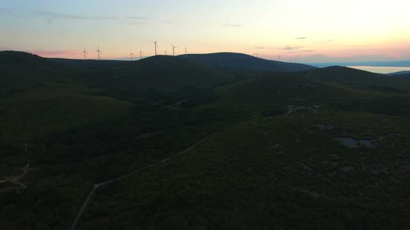 Sun setting behind hills with windmills in the background