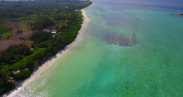 Wide flying abstract shot of a sandy white paradise beach and aqua blue ocean background in 4K