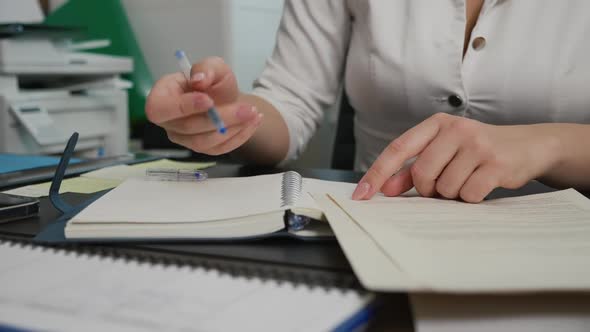 Young Female Doctor Knocks on Table with Pen and Starts Writing in Notebook