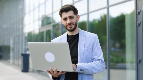 Successful Bearded Businessman Freelancer is Staing Near Modern Office and Smiling at the Camera