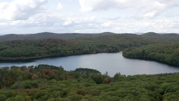 Picturesque lake in a vast forest - aerial pull back view in autumn