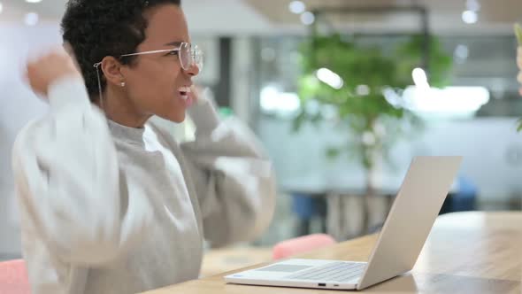 Excited Casual African Woman Celebrating Success on Laptop