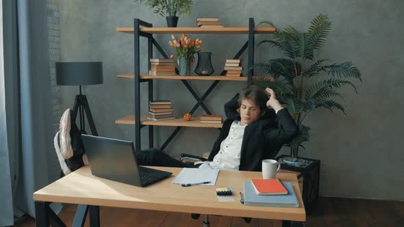 Young Attractive Businessman is Resting From Work with His Legs on the Table