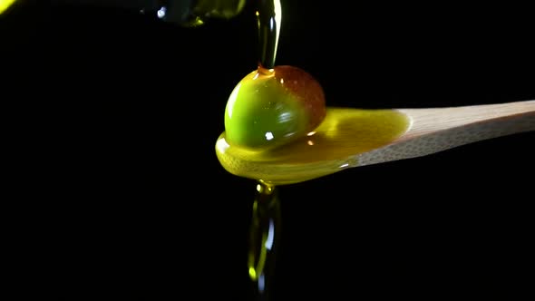 Close-up of olive oil is  pouring on a green olive 