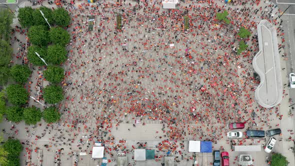 Drone Descending Shot Above a Crowd of Protesters in Orange Shirts. Wide daytime exterior overhead b