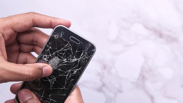 Close Up of Man Hand Holding Broken Smart Phone.