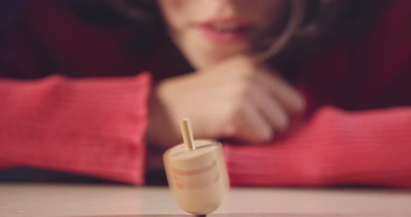 Close up shot of a girl spinning a Hanukka dreidel on the floor