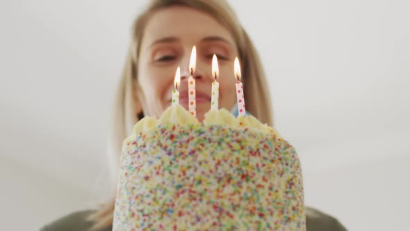 Woman blowing candles on the cake at home