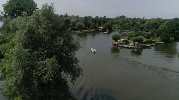 Aerial Slomo Revealing Dutch Countryside with a Small Motorboat sailing with Male Friends, surrounde