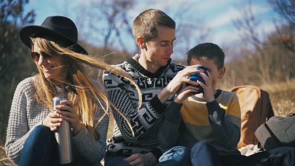 A Happy Family Having a Good Time While Drinking Tea From a Thermos Outdoors