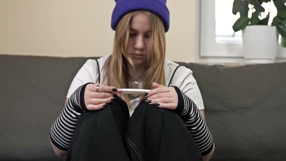 Teenage Girl Looks at the Result of a Pregnancy Test and Cries