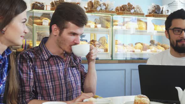 Young People Chatting Over Cup of Coffee at the Cafe 