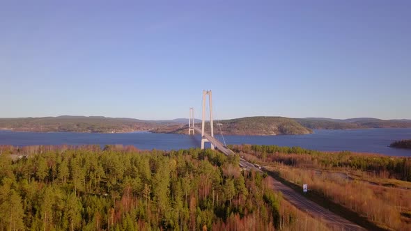 Aerial drone view towards a bridge, between hills, lakes and forest, on a sunny spring day, in Hoga