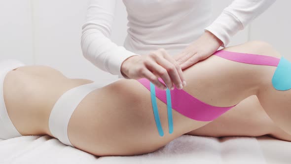 Therapist is applying kinesio tape to female body. Physiotherapy, kinesiology and recovery.