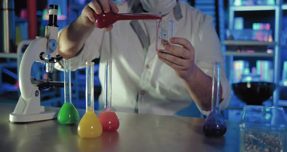 Scientist Pours Liquid From One Flask to Another