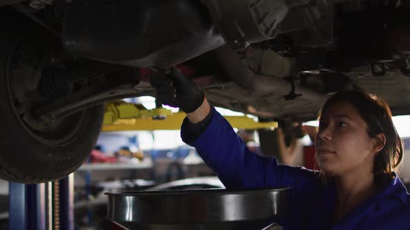 Female mechanic changing oil of the car at a car service station