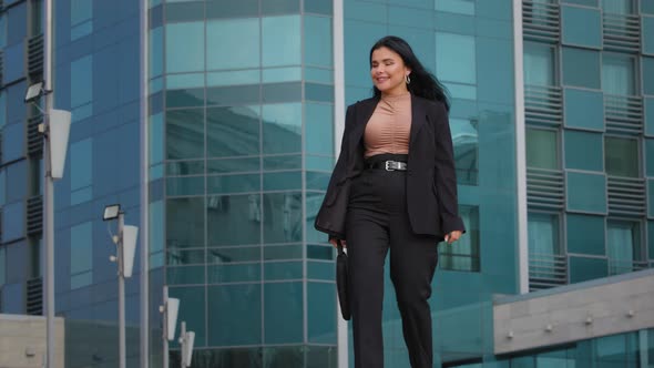 Young Hispanic Woman Walking Down Street Carrying Briefcase Looks Around Happy Student Girl Jumps