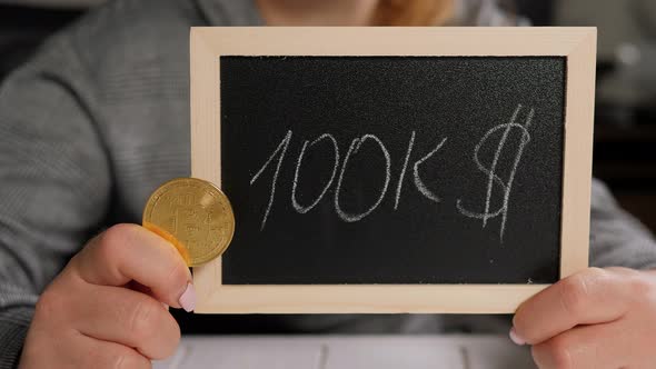 A Woman Holding a Board with the Inscription 100 Thousand Dollars for Bitcoin