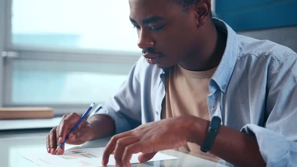 Serious Young American Businessman Checking Corporate Paperwork at Office Desk