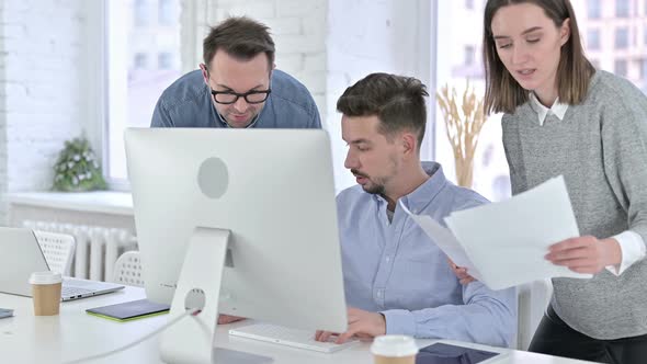 Focused Startup Team Discussing Documents and Working on Desktop