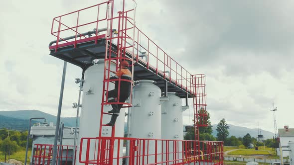 Aerial View Gas Station Operator Climbs To the Top of the Station. Modern Gas Complex in the