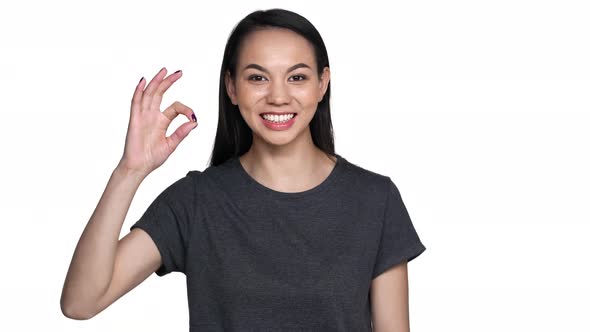 Portrait of Positive Asian Woman with Long Dark Hair in Casual Clothing Gesturing Ok Symbol and