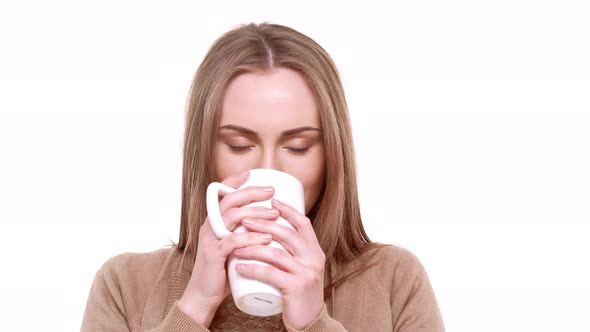 Young Beautiful Caucasian Female with Light Brown Hair Standing on White Background Drinking Hot Tea