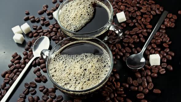 Rotating Two Cups with Coffee on Coffee Beans and Carica Sticks