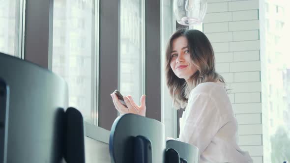 Lovely Woman Smiling To the Amera Using Smart Phone at Coffee Shop