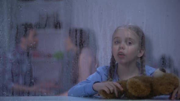 Little Girl With Teddy Bear Showing No Gesture on Rainy Day, Parents Quarrelling