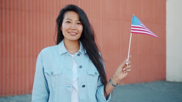 Portrait of Pretty Asian Girl Holding US Flag Outdoors Smiling Looking at Camera