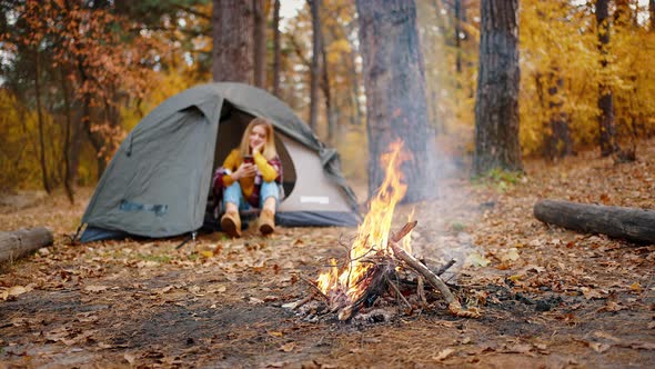 Young Woman Sitting in Tent and Using Her Smartphone