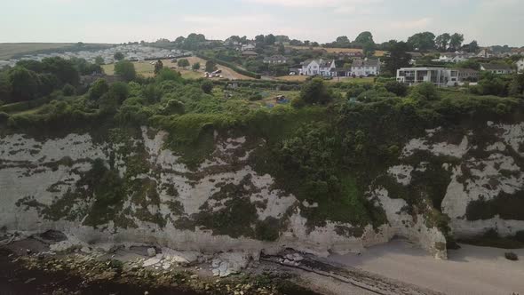 Aerial view over looking the cliffs of Beer Beach and some homes above it. The sandy beach can be se