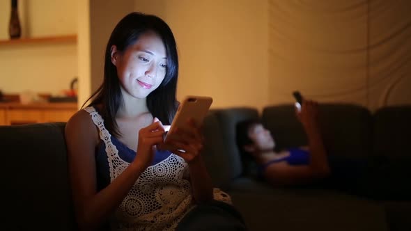 Woman use of mobile phone and sitting on sofa at night