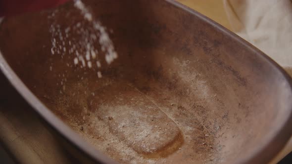 BAKING - Sprinkling flour on a clay baker, sourdough bread baking, slow motion