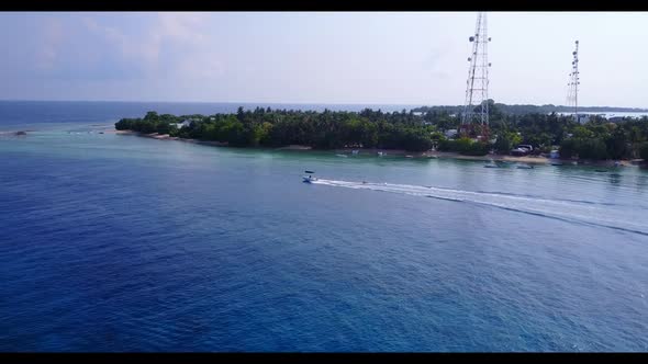 Aerial drone shot tourism of beautiful shore beach break by blue green water with bright sandy backg