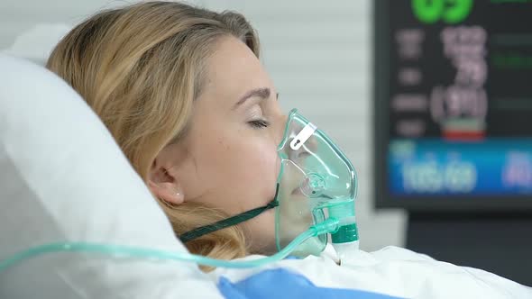 Female Patient Lying Hospital Bed With Oxygen Mask, Monitor Showing Vital Signs