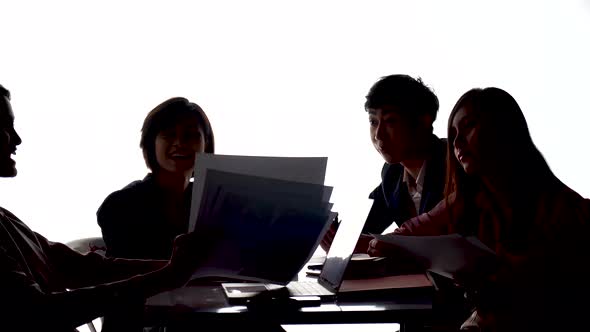 Silhouettes of people sitting at the table,Group of businesspeople high five together in a boardroom