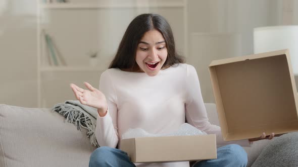 Amazed Arabian Latino Female Customer Shopper Buyer Sitting on Sofa Unpacking Postal Shipping