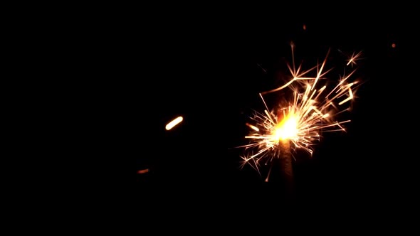 Festive Sparkler Emits Sparks on a Black Background Closeup
