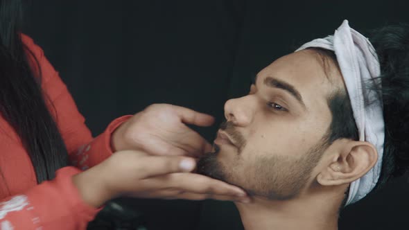 Close up of make up artist and man on cosmetics treatment in cosmetics studio