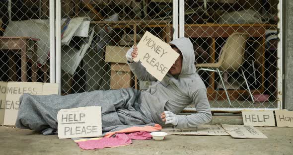 Homeless man sleeping, sitting and holding money please label.