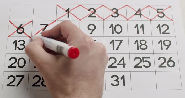 Man's Hand Write Down the All Day on the Paper Calendar Using a Red Pen