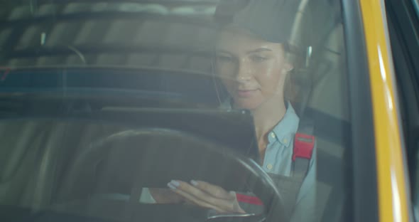 Auto Mechanic Uses Tablet Computer To Inspect Technical Condition Sitting Behind the Wheel of a New